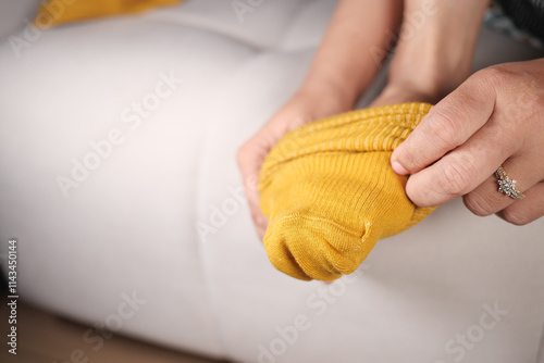 Hands Putting On Cozy Yellow Socks in a Relaxing Home Environment photo