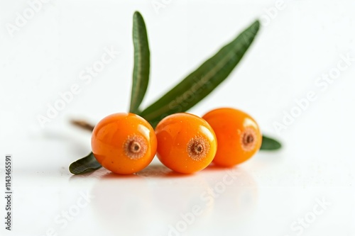 Close-up of three vibrant sea buckthorn berries with leaves. A close-up image of three fresh, ripe sea buckthorn berries, each with a glossy, orange-yellow hue, set against a bright white background. photo