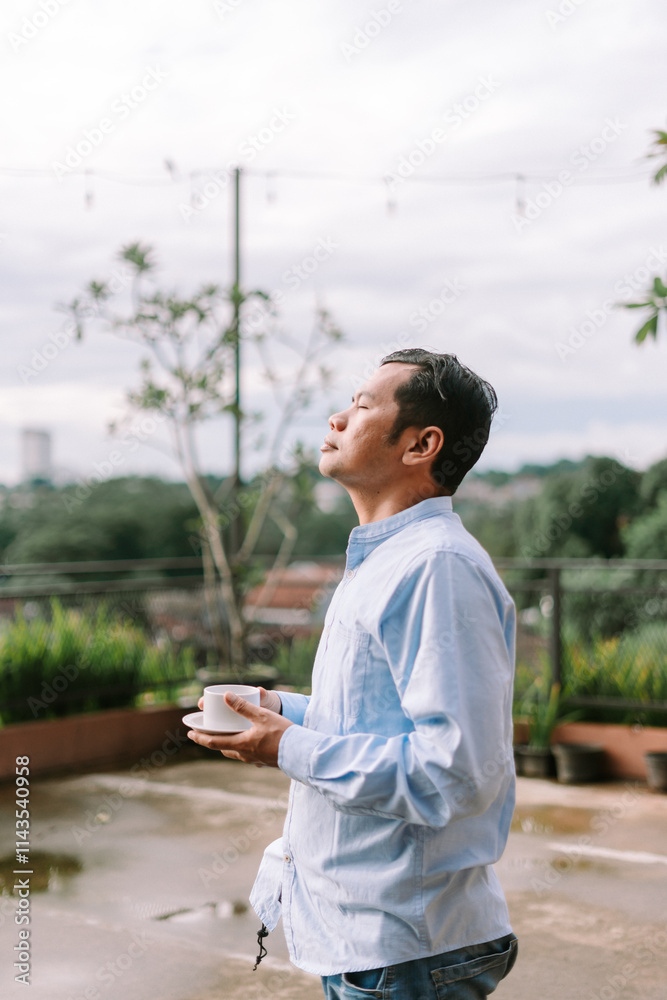 Fototapeta premium A Southeast Asian man enjoying a sip of coffee on a peaceful morning