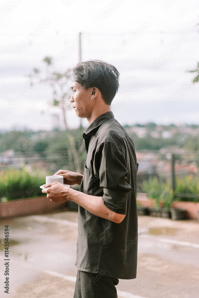 A Southeast Asian man enjoying a sip of coffee on a peaceful morning A Southeast Asian man enjoying a sip of coffee on a peaceful morning