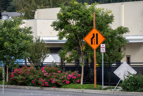 Orange left lane merge sign, Lane Reduction Transition Sign, as a caution in an urban construction zone, transportation background
 photo