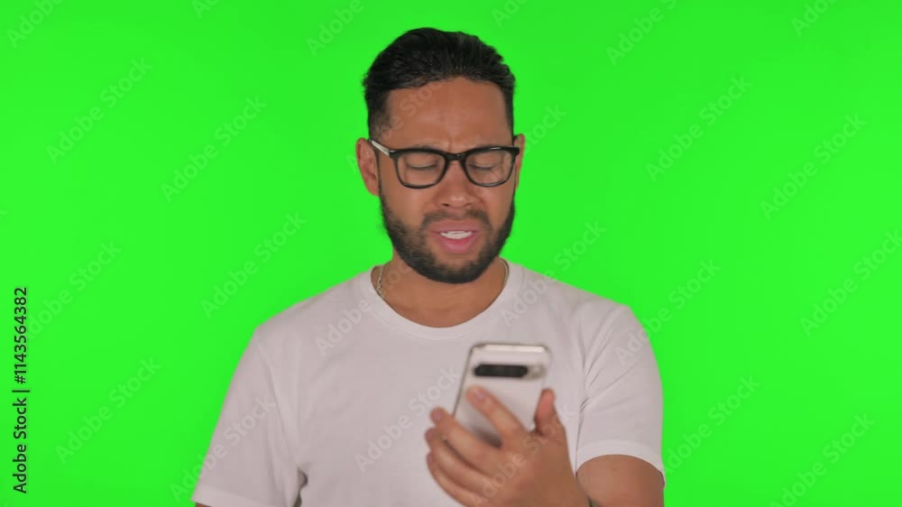 Man Shocked by Loss on Phone on Green Background Man Shocked by Loss on Phone on Green Background