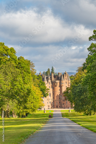 The tree-lined avenue to the old historical Glamis Castle in Scotland with green trees