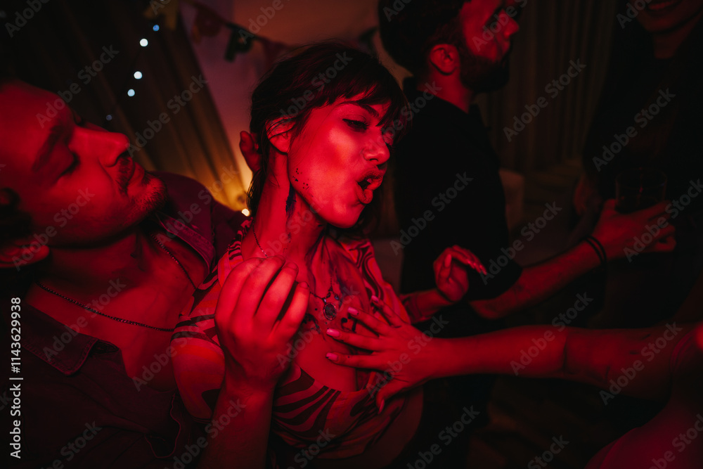 A group of young adults enjoying a lively birthday party with energetic dancing and laughter under atmospheric red lighting. A group of young adults enjoying a lively birthday party with energetic dancing and laughter under atmospheric red lighting.