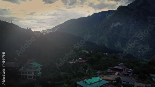 Beautiful drone shot of a village in Parvati valley with old rustic houses at the foothills of Himalayas in Himachal Pradesh, India