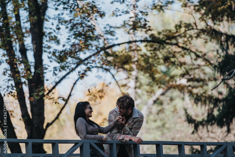 A happy couple shares a playful moment on a bridge surrounded by vibrant forest foliage. They are smiling and enjoying the serene natural setting on a sunny day. A happy couple shares a playful moment on a bridge surrounded by vibrant forest foliage. They are smiling and enjoying the serene natural setting on a sunny day.