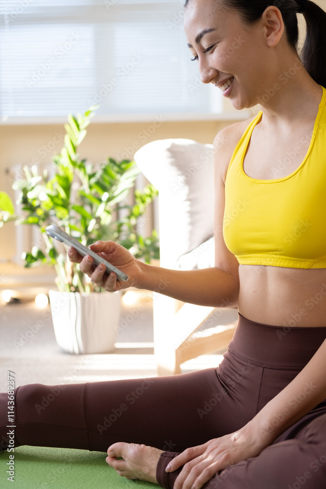 Beautiful young asian woman is looking at smartphone, listening music and relaxing after training. Beautiful young asian woman is looking at smartphone, listening music and relaxing after training.