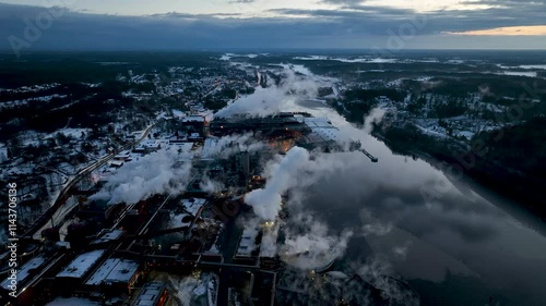 Aerial view of paper mill Industrial plant emitting smoke over river at sunset photo