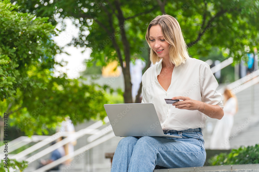 Caucasian Woman Using Laptop and Credit Card to Perform Online Transaction While Sitting Outdoor a Park Caucasian Woman Using Laptop and Credit Card to Perform Online Transaction While Sitting Outdoor a Park
