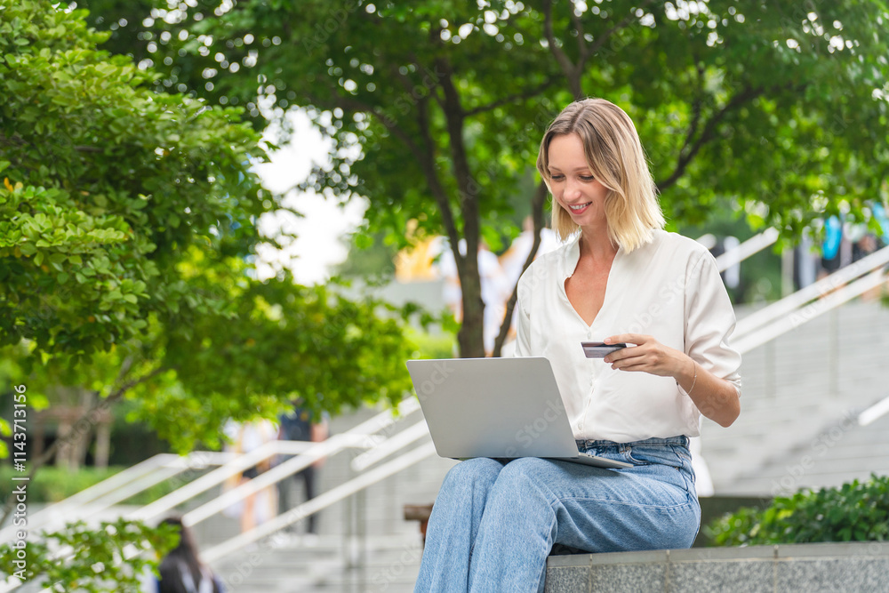 Caucasian Woman Using Laptop and Credit Card to Perform Online Transaction While Sitting Outdoor a Park Caucasian Woman Using Laptop and Credit Card to Perform Online Transaction While Sitting Outdoor a Park