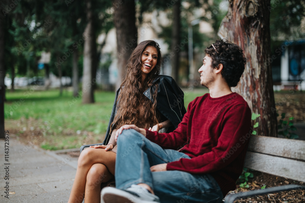 A joyful young couple shares a lively conversation on a park bench, surrounded by greenery and trees, expressing happiness and connection in an outdoor setting. A joyful young couple shares a lively conversation on a park bench, surrounded by greenery and trees, expressing happiness and connection in an outdoor setting.