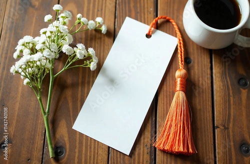 Blank bookmark mockup with orange tassel next to white flowers, on wooden background, top view. Price tag mockup
