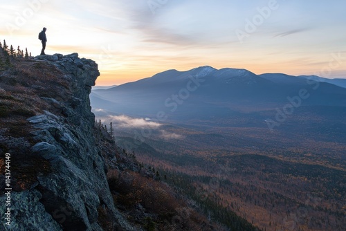 Panoramic mountainous landscape lone hiker silhouette rocky cliff edge misty distant peaks