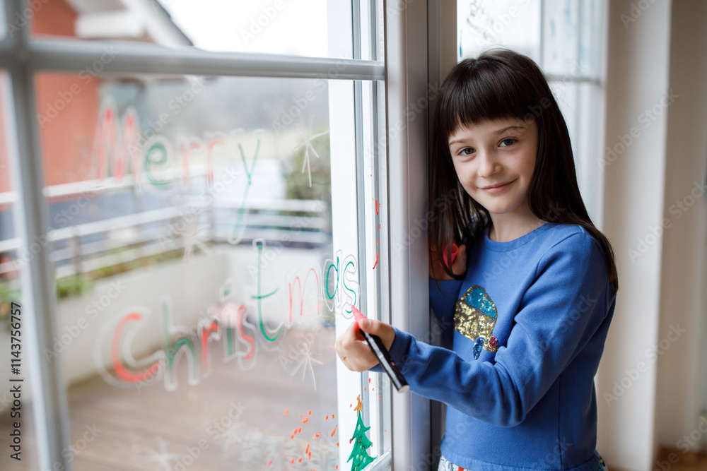Cute little girl drawing merry christmas wishes on window Cute little girl drawing merry christmas wishes on window