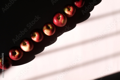 Eight dramatically Lit Apples with Heavy Shadows on Lilac Backdrop photo