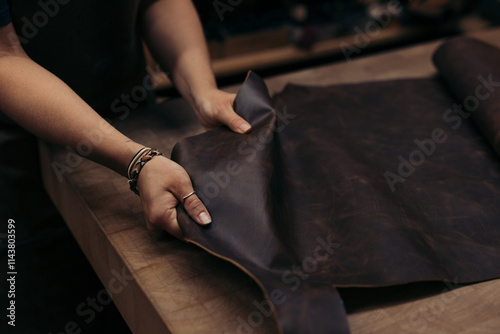 Artisan handling rich brown leather sheet for tailoring crafts