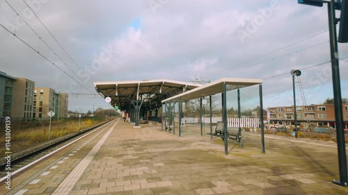 Empty platform at Geldrop train station with a detailed view of its shelter and tracks, capturing a peaceful, functional public transit space in Noord Brabant, Netherlands photo
