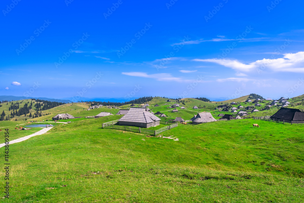 Traditional wooden houses covering the green hills of velika planina in slovenia Traditional wooden houses covering the green hills of velika planina in slovenia