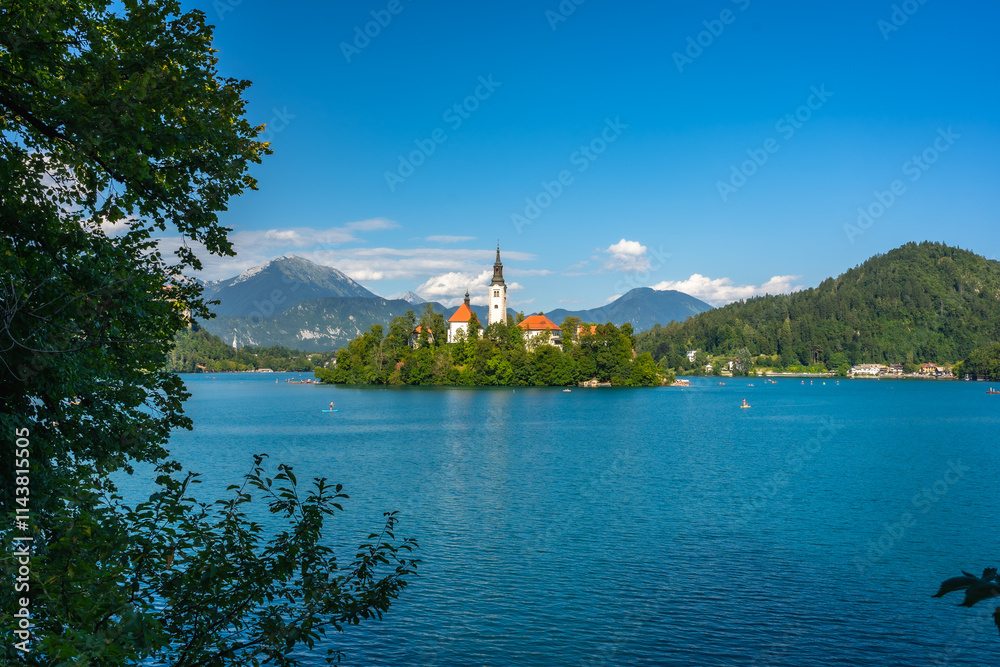 Lake bled island church framed by lush green trees on sunny summer day Lake bled island church framed by lush green trees on sunny summer day