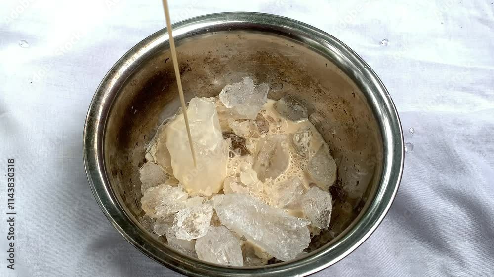 A bowl filled with ice and a stick pouring a creamy mixture, likely for dessert preparation. A bowl filled with ice and a stick pouring a creamy mixture, likely for dessert preparation.
