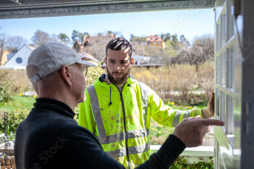 Side view of mature man talking to painter during renovation work photo