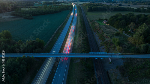 Wallpaper Mural Drone view of bridge above two lane illuminated highway amidst agricultural field at dusk Torontodigital.ca