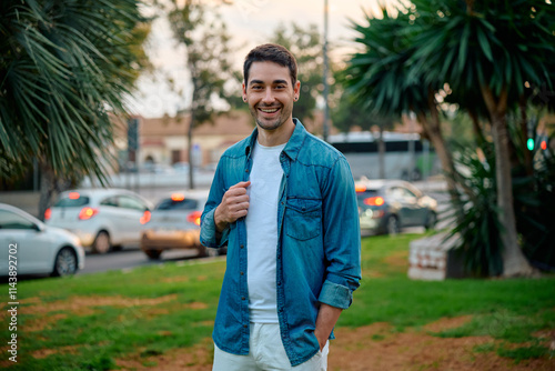 Young man smiles in a park while casually dressed during sunset photo