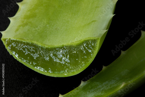 Close view of a sliced fresh juicy aloe vera leaf on black background