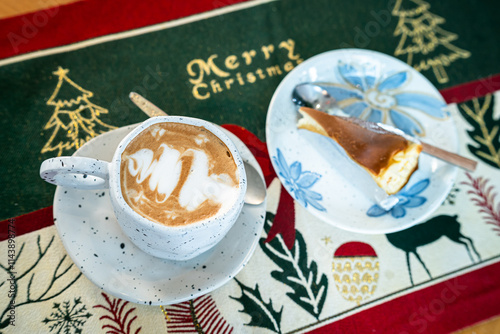 Obraz na płótnie Close up of Hot coffee latte with latte art milk foam in cup mug and Homemade burnt cheesecake with Xmas decors and Xmas tree baubles on wood desk Celebrating Merry Christmas and New year,Merry x-mas w salonie
