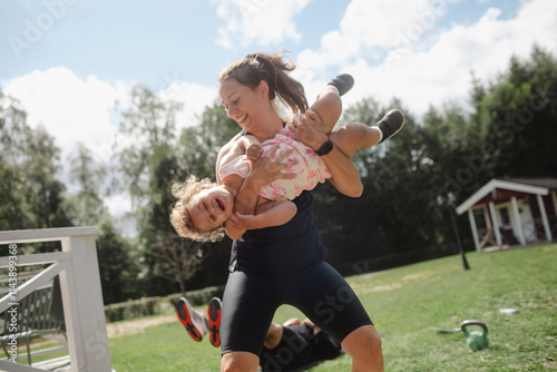 Cheerful mid adult woman playing with daughter in yard