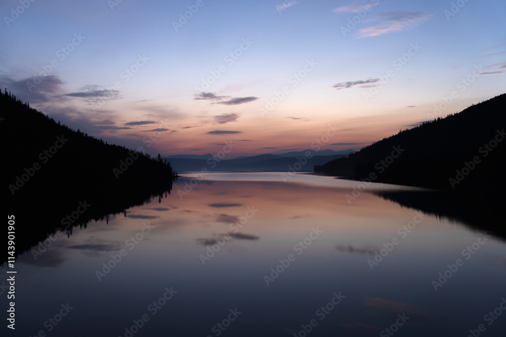 Calm lake against dramatic sky at dusk Calm lake against dramatic sky at dusk