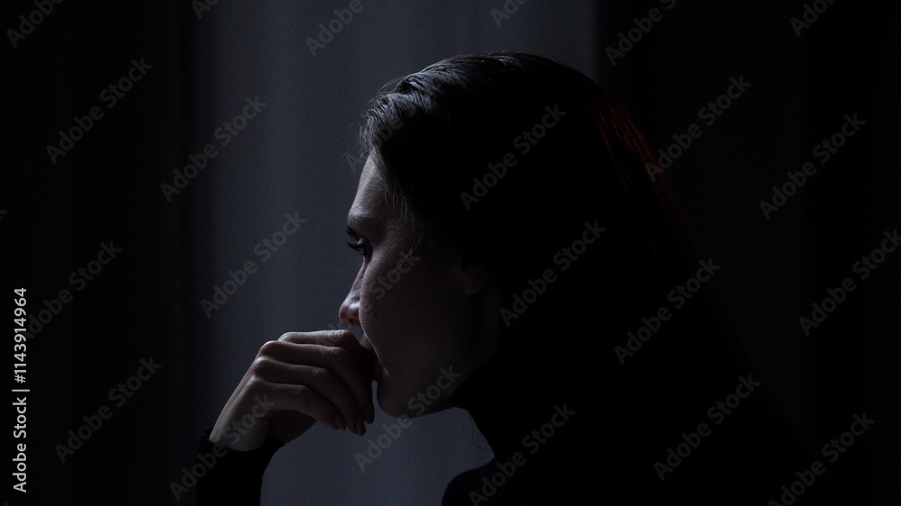Silhouette of woman with mental health issues, sitting on the sofa, depressed expression, deep thinking, looking indifferent, hands touching chin, close shot. Silhouette of woman with mental health issues, sitting on the sofa, depressed expression, deep thinking, looking indifferent, hands touching chin, close shot.