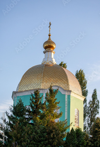 A tall building with a gold dome and a cross on top