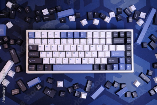 Modern 75% Layout White Mechanical Keyboard With Minimalist Theme of White, Blue, and Black Keycaps on a Blue Deskmat, with Scattered Keycaps