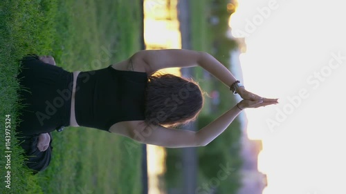 Girl doing yoga, meditating in the park at sunset.