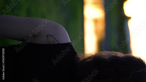 Girl doing yoga, meditating in the park at sunset.