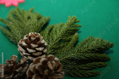 Season's greetings scene.Share your warm wishes with this image idea.view of magnificent giftbox with ribbon, sparkling ornaments, frosty fir, ball, cone on green backdrop, ready for personalized ad photo