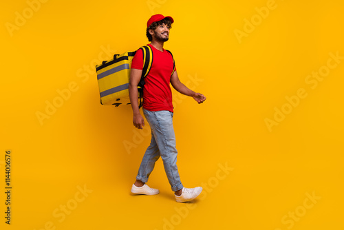 Young deliveryman walking confidently against a vibrant yellow background wearing casual and trendy attire