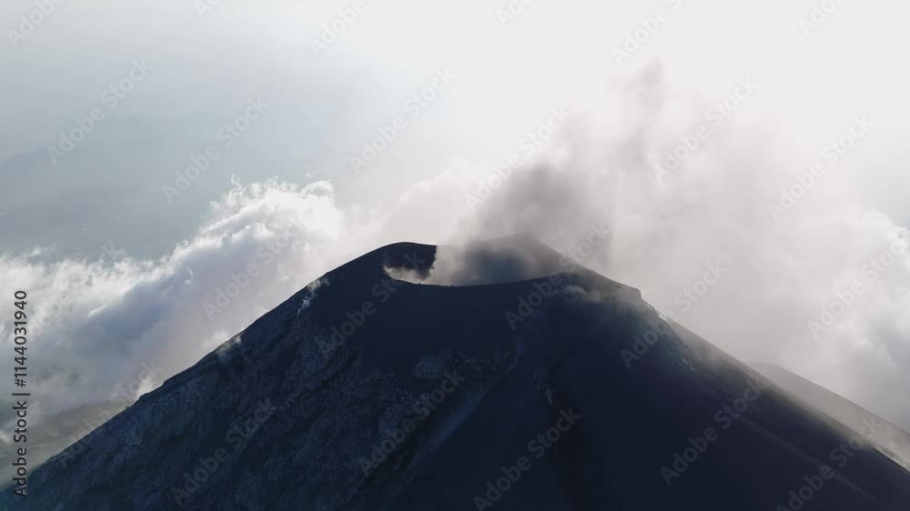 Detailed view of the active crater of Volcan de Fuego, Guatemala, with smoke and clouds creating a dramatic atmosphere.