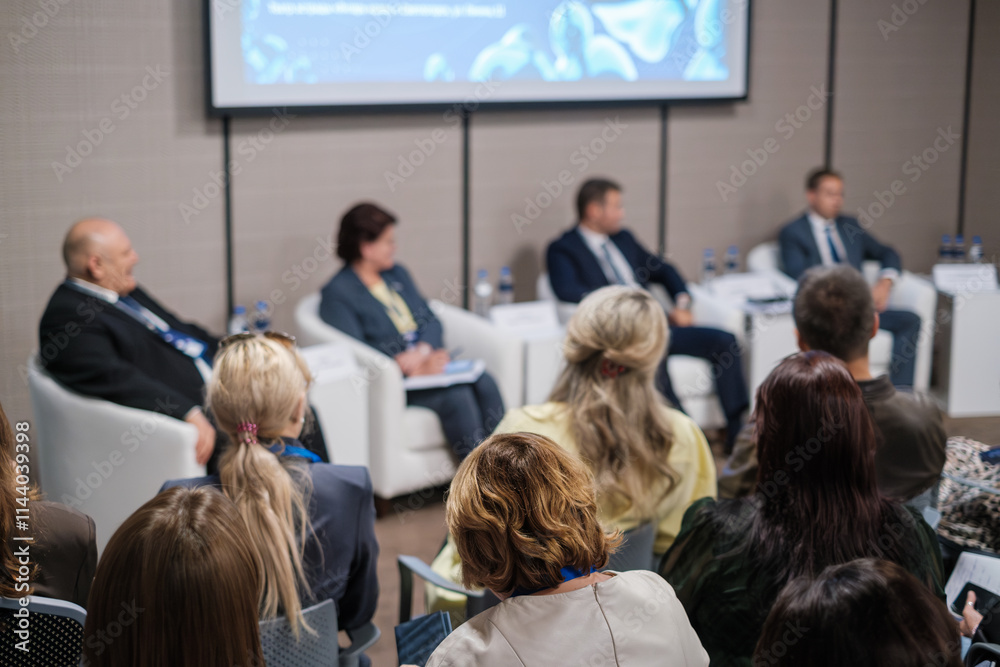 Fototapeta premium Audience attending panel discussion with professional speakers sharing insights on business trends and strategies