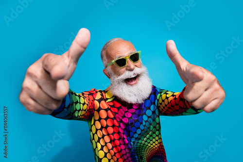 Photo of funny stylish aged man point fingers you wear colorful shirt isolated on blue background photo