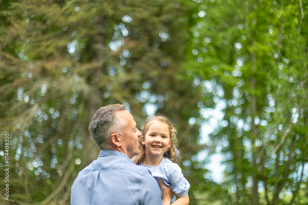 Father holding his smiling daughter in a green park Father holding his smiling daughter in a green park