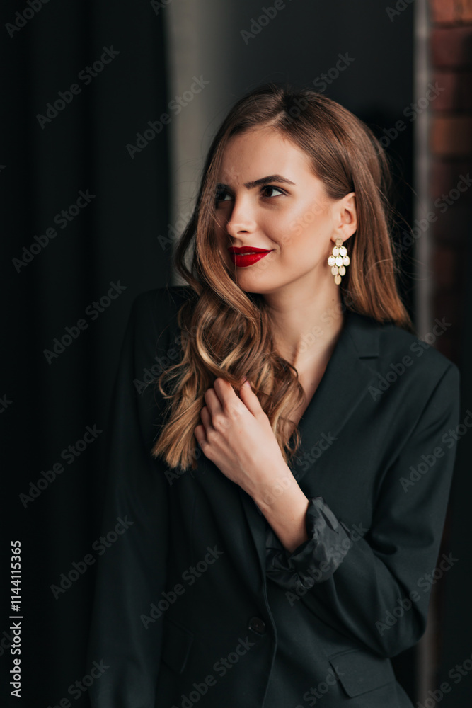 Portrait of a cheerful young woman wearing black jacket standing isolated over black background, looking aside with romantic smile