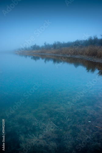 Autumn morning on the blu lake with fog , reflections on water ,landscape photography .Blue colors ,blue water ,mystery weather on the ponf.Forest near the pond , morning landscape at autumn season photo