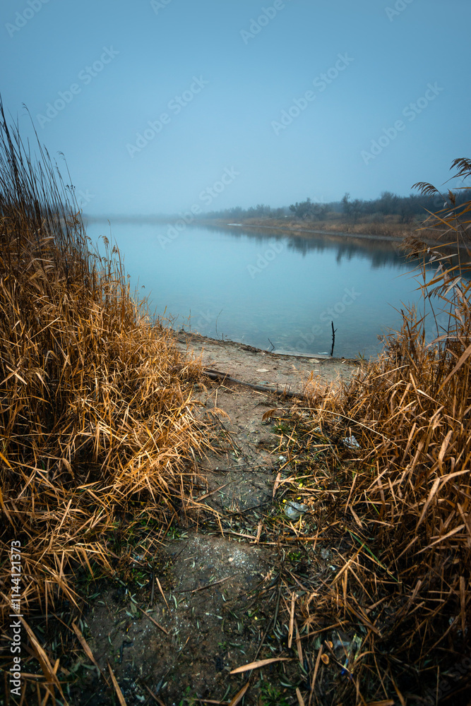 Fototapeta premium Autumn morning on the blu lake with fog , reflections on water ,landscape photography .Blue colors ,blue water ,mystery weather on the ponf.Forest near the pond , morning landscape at autumn season