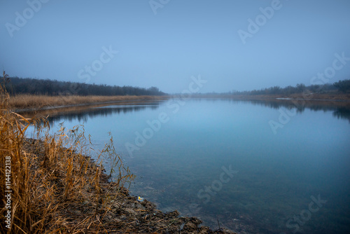 Autumn morning on the blu lake with fog , reflections on water ,landscape photography .Blue colors ,blue water ,mystery weather on the ponf.Forest near the pond , morning landscape at autumn season photo