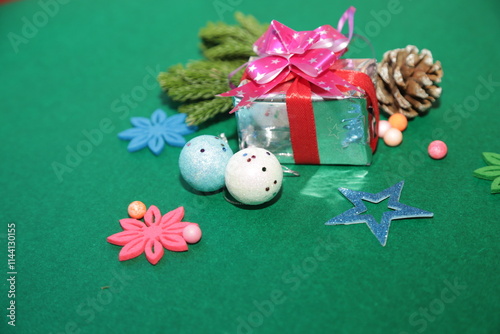 Christmas festivity theme. view of beige present packages, sophisticated tree ornaments, baubles, handcrafted star, mistletoe sprigs, snowman on green backdrop, space for ad
 photo