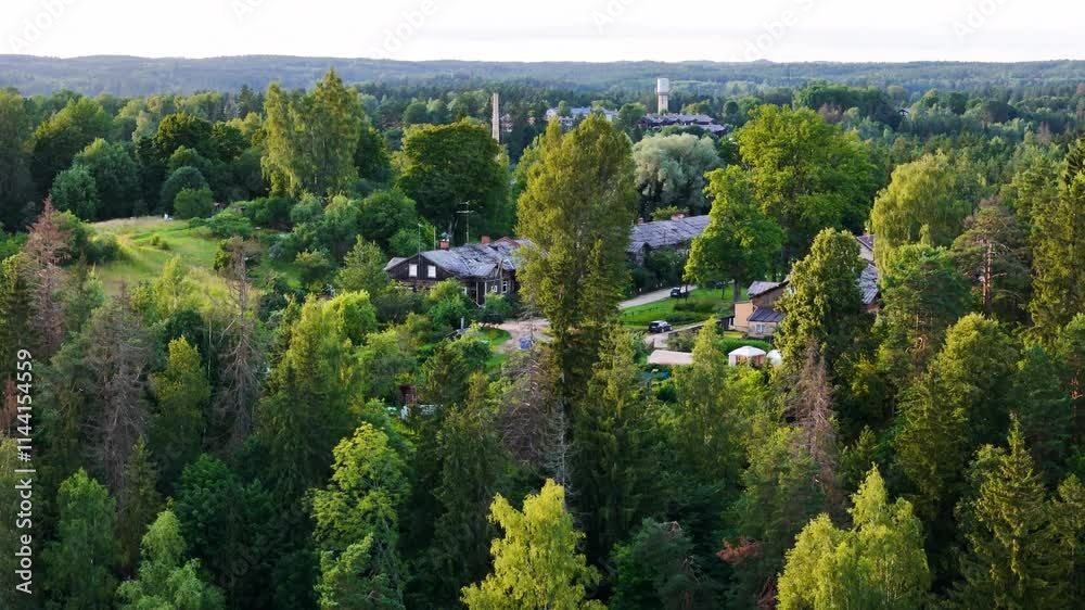 aerial view at sunset of Līgatne town Latvia drone fly above forest tree with old paper factory in east Europe aerial view at sunset of Līgatne town Latvia drone fly above forest tree with old paper factory in east Europe