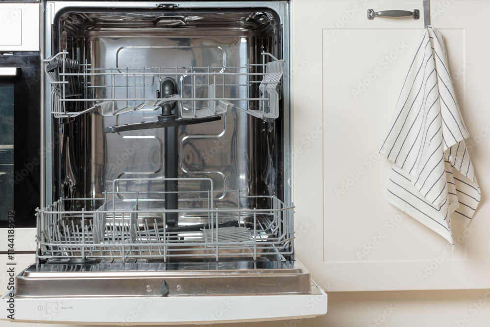 Built-in empty dishwasher with its door open. Modern technologies in the home kitchen with minimalistic white cabinetry. Simplifying daily housework. Built-in empty dishwasher with its door open. Modern technologies in the home kitchen with minimalistic white cabinetry. Simplifying daily housework.
