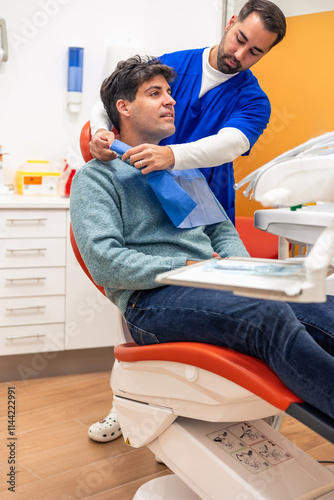 Dentist placing a bib on patient before dental checkup
